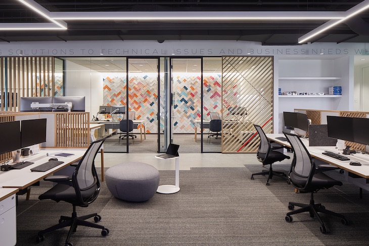 Open work area, wood/glass screen wall, and private offices in the background